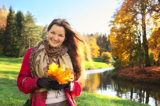 beautiful girl with bunch of maple leaves in autumn park