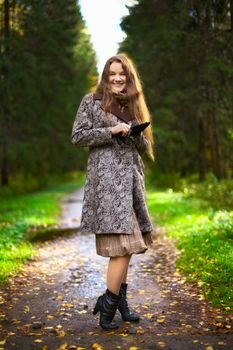beautiful girl standing in autumn park alley