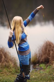 beautiful blond girl fishing in pond at autumn