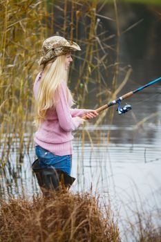 beautiful blond girl in pink sweater fishing