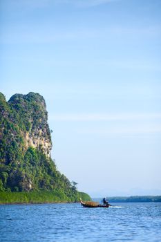 tall cliff in sea and fisherman in boat, Andaman Sea, Thailand