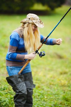 beautiful blond girl fishing in pond at autumn