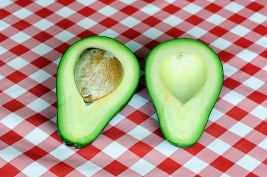An image of sliced open avocado on tablecloth