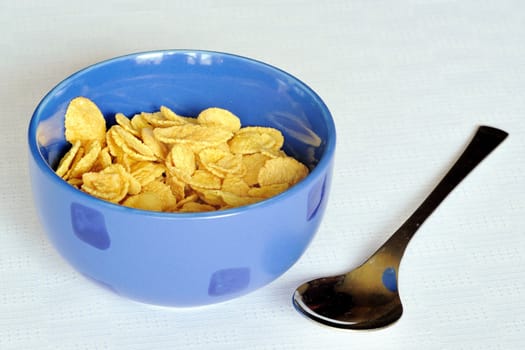 Cereal flakes in a blue bowl on white background