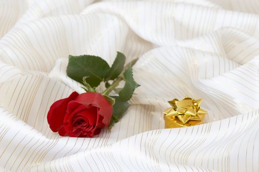 Rose and jewelry on background of fabrics