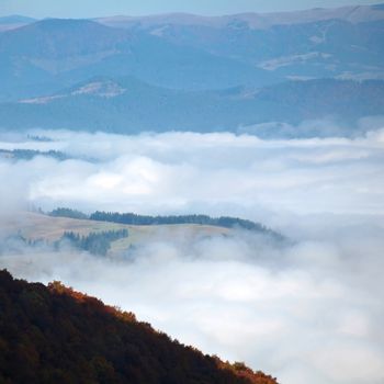 An image of fluffy clouds on the mountains