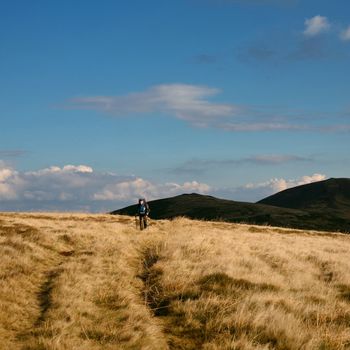 Nature theme: tourist walking in autumn mountains