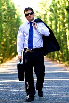 View of a young male business man on a asphalt road.