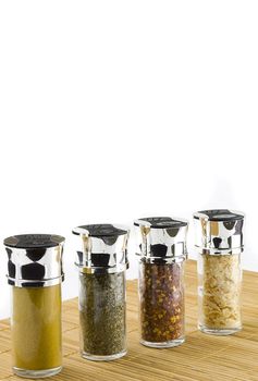 different spices in glass jars on wooden mat