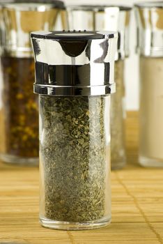 dry parsley in a glass jar on different spices background over wooden mat