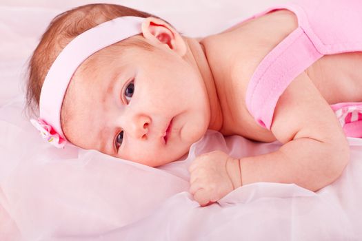 View of a newborn baby on smooth bed.