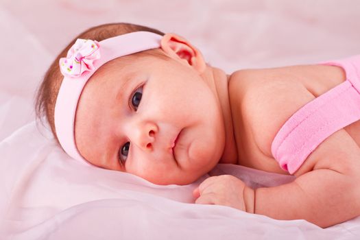 View of a newborn baby on smooth bed.