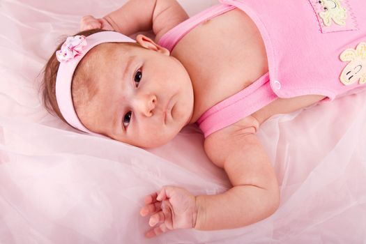 View of a newborn baby on smooth bed.