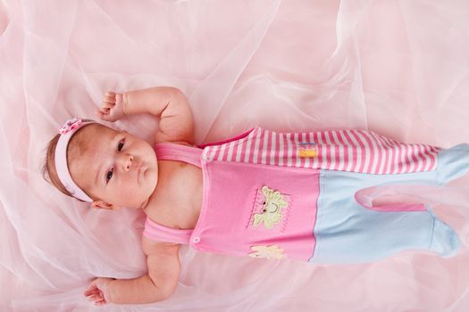 View of a newborn baby on smooth bed.