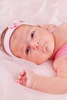 View of a newborn baby on smooth bed.