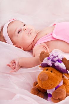 View of a newborn baby on smooth bed with toy.