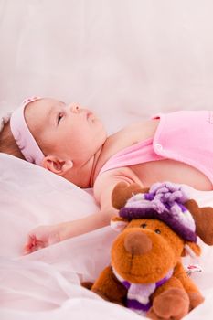 View of a newborn baby on smooth bed with toy.