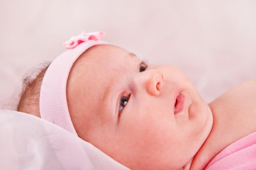 View of a newborn baby on smooth bed.
