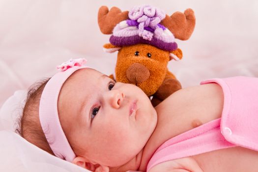 View of a newborn baby on smooth bed with toy.