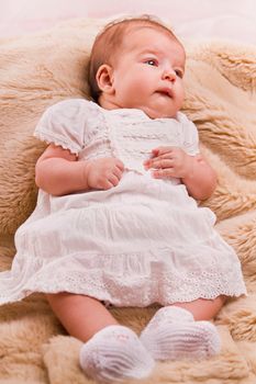 View of a newborn baby on a smooth bed.