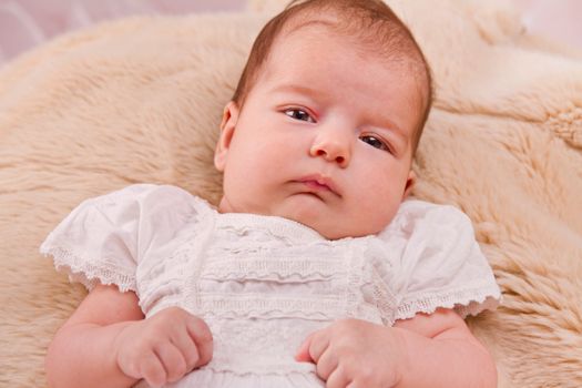 View of a newborn baby on a smooth bed.