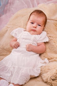 View of a newborn baby on a smooth bed.