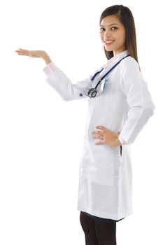 Happy cheerful beautiful Asian young Doctor holding her hand out and showing copy space for your product.