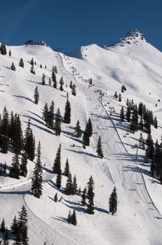 Snow covered ski piste surrounded by trees on sunny day at Montafon, Austria