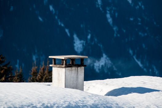 Chimney on snow covered roof of skiing hut in Montafon, Austria