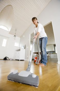 Woman cleaning the house with the Vacuum Cleaner