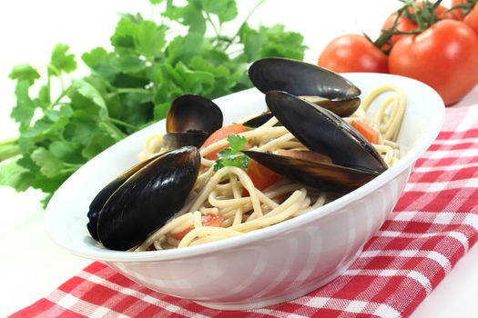 freshly cooked Spaghetti with tomatoes, mussels and parsley on a light background
