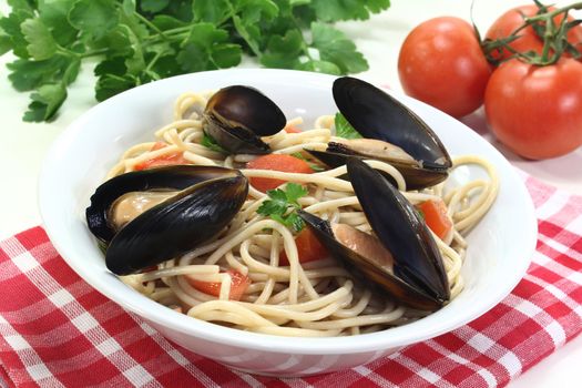 cooked Spaghetti with tomatoes, mussels and fresh parsley on a light background