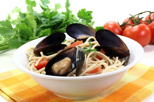 cooked Spaghetti with tomatoes, mussels and parsley on a light background