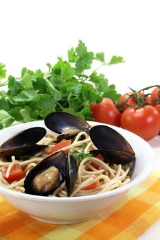 Spaghetti with tomatoes, mussels and parsley on a light background