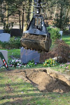 The digging of a grave with a middle sized digging machine