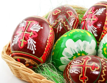 Group of painted Easter eggs in wooden basket isolated on a white background (Extreme closeup)