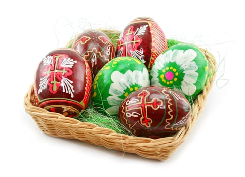 Group of painted Easter eggs in wooden basket isolated on a white background