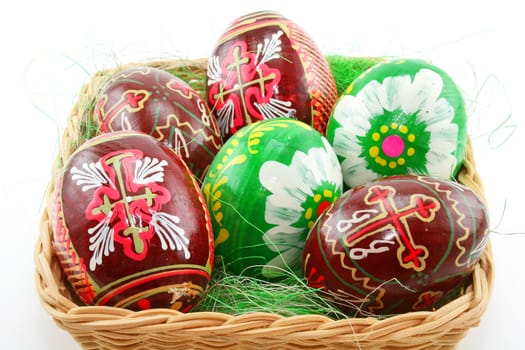 Group of painted Easter eggs in wooden basket isolated on a white background