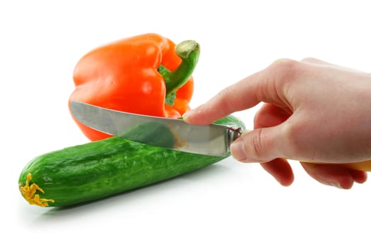 Woman's hand cuting green cucumber and orange paprika isolated on a white background