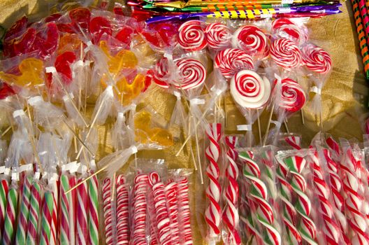 Various forms colorful sucked lollipops sold at outdoor street market fair. Sweets.