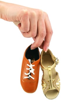 Female hand holds tiny dancing shoes (men's and woman's) isolated on a white background
