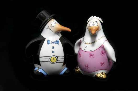 two penguin figurines on a black background