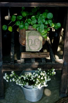 Decorative Buddha art at wooden table with nice flower and plant