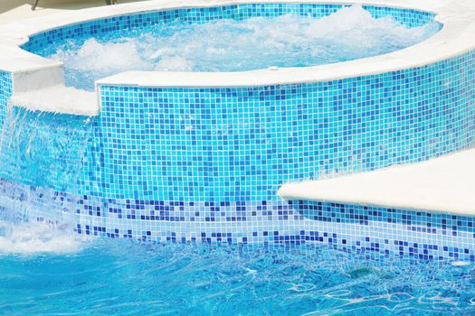 Empty Swimming pool with waterfall jet and jacuzzi in action