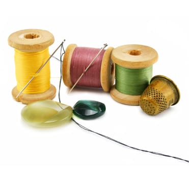 Spool of thread, thimble and needle isolated on a white background