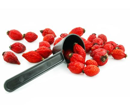 Rose hips and measuring spoon isolated on a white background