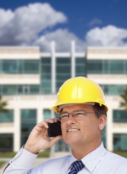 Handsome Contractor in Hardhat and Necktie Smiles as He Talks on His Cell Phone in Front of Building.