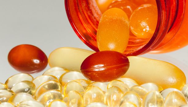 Various sorts of fish oil tablets spilling from prescription bottle onto table