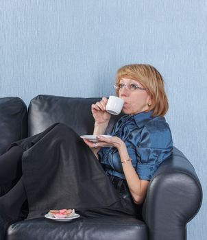 Portrait of relaxed middle aged woman drink coffee on couch