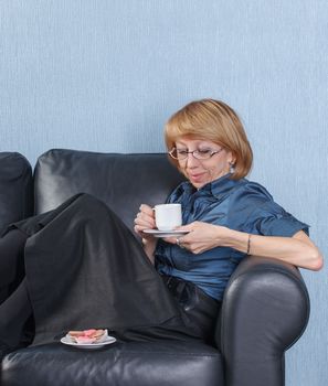 Portrait of relaxed middle aged woman drink coffee on couch